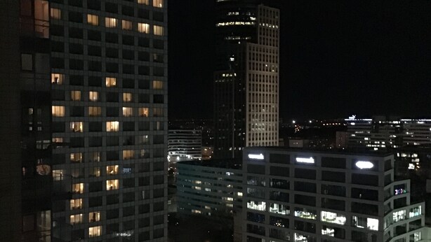A nighttime cityscape with illuminated high-rise buildings, including a hotel with a prominent sign. - Green Wood Apartments Platinum Towers (Warsaw)