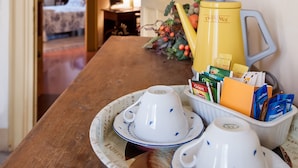 A dining table with teapots, cups, and a tray of food items. - La Casa di Zoe (Palermo)