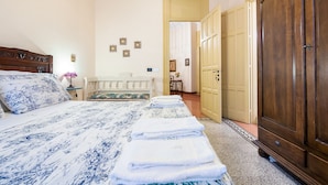 A bedroom with a bed, a bedside table, a lamp, a wardrobe, and a door leading to another room. - La Casa di Zoe (Palermo)