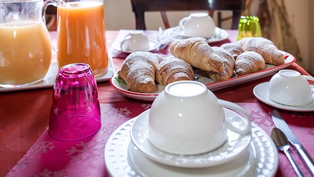 A breakfast table with croissants, a pitcher of orange juice, and a cup of coffee. - La Casa di Zoe (Palermo)