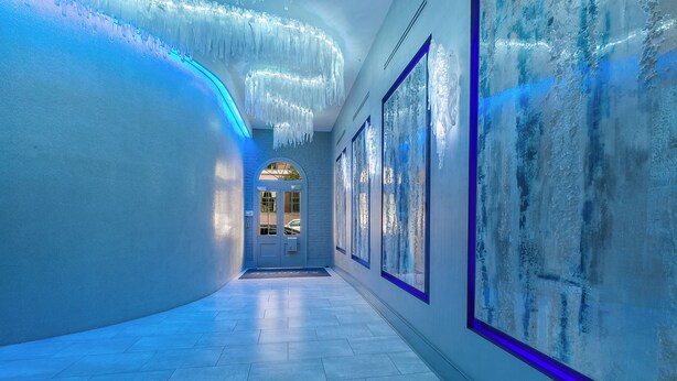 A hallway with a blue-lit wall, a chandelier, and framed artwork. - WHERE GLAM MEETS COZY! THE PERFECT PLACE FOR A DOWNTOWN GETAWAY! | The Sazerac (New Orleans)
