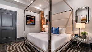 A modern hotel room with a four-poster bed, a brick accent wall, and a large mirror.