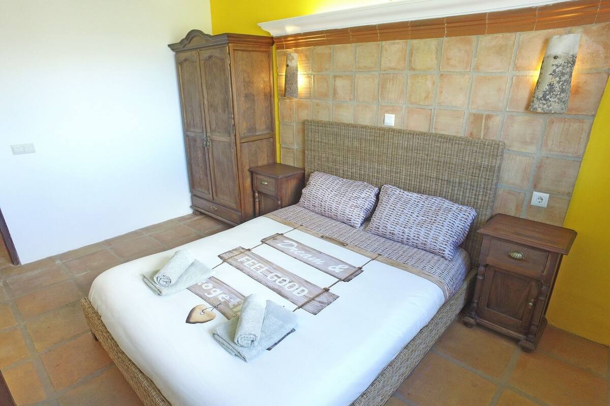 A neatly made bed with a white comforter and a decorative headboard.