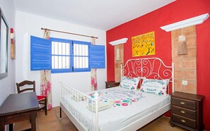Una camera da letto con un letto, una sedia, un comò e una finestra con persiane blu.