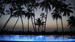 A poolside view with palm trees and a sunset. - Soluna Beach Resort (Marawila)