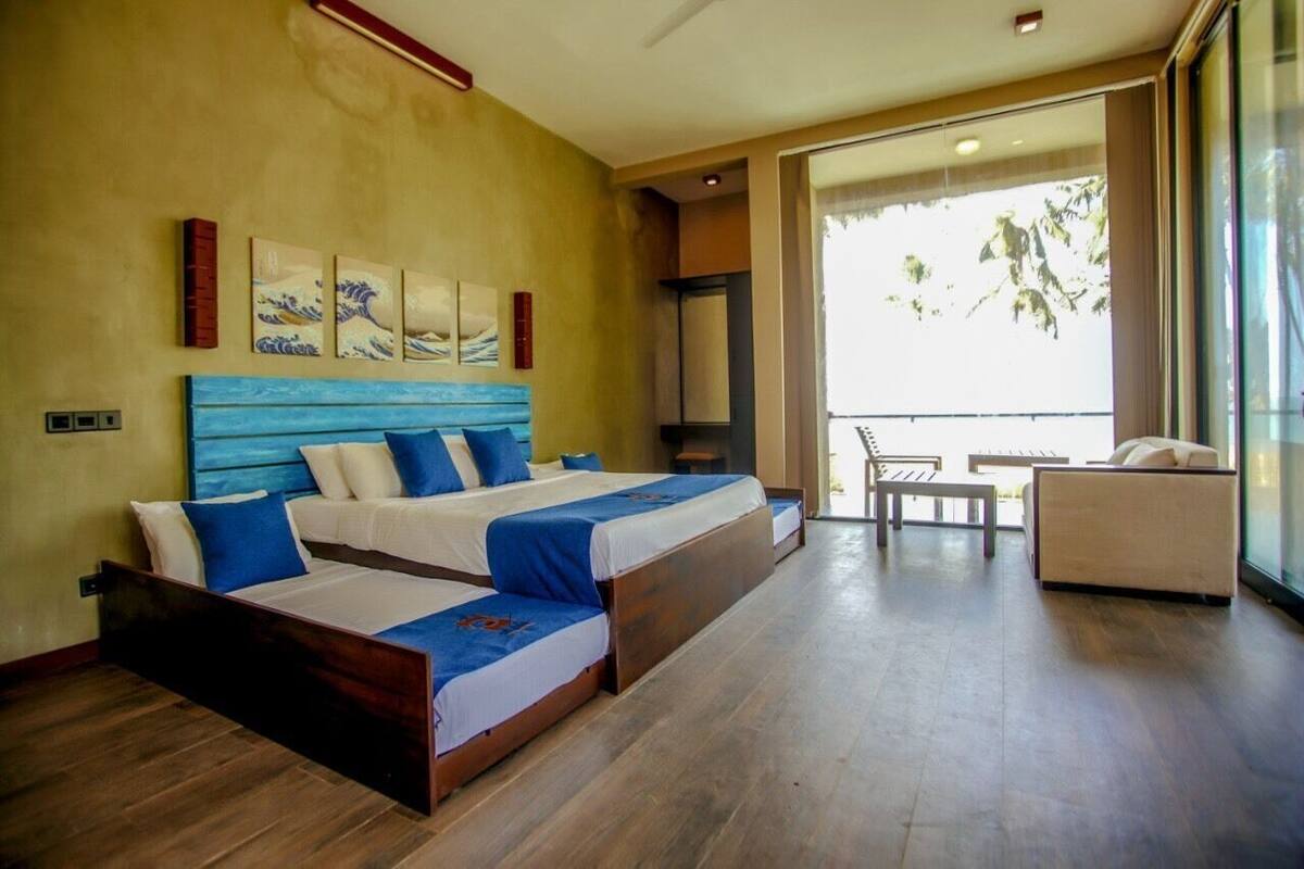 A hotel room with two beds, a balcony with a view, and a seating area.