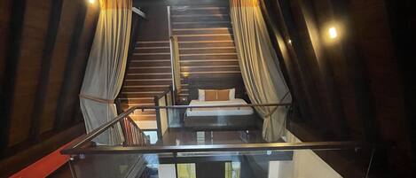 Un dormitorio tipo loft con una cama, un escritorio pequeño y una escalera que conduce a un nivel superior.