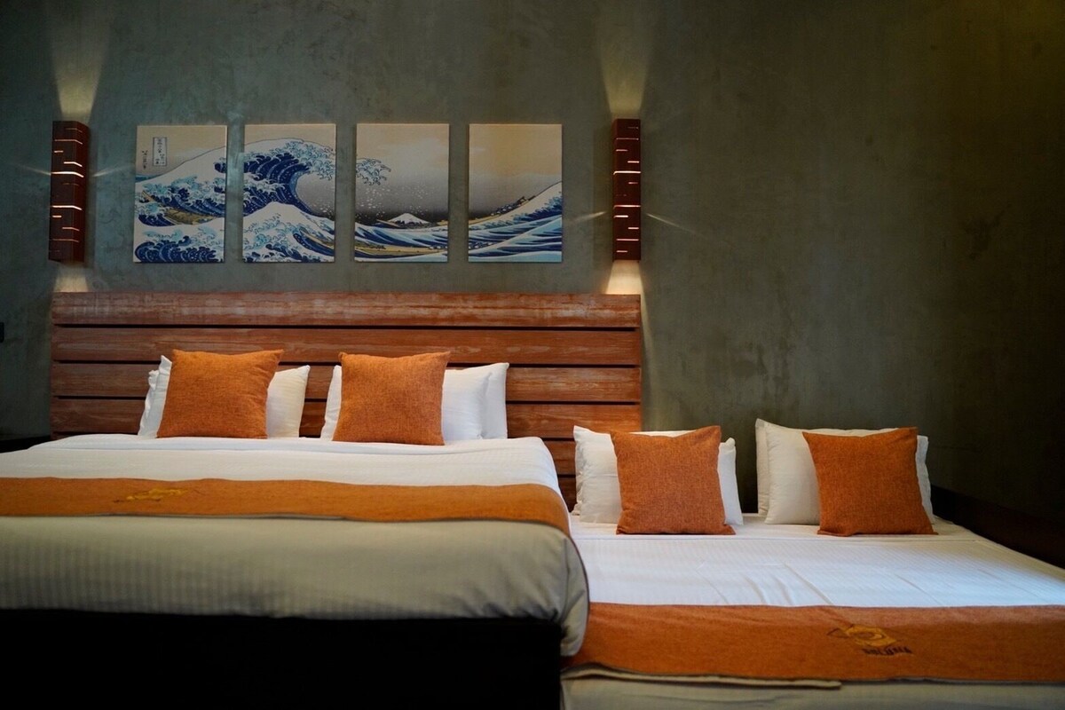 A hotel room with a large bed, a wooden headboard, and a wall-mounted artwork of waves.