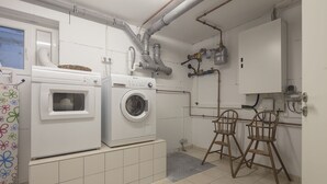 Ein Waschraum mit Waschmaschine, Trockner und einer kleinen Sitzecke mit zwei Holzsesseln.