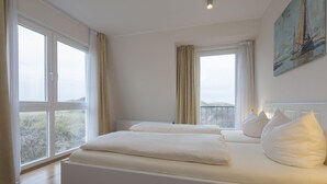 Ein Schlafzimmer mit einem großen Bett, zwei Fenstern und einem Bild an der Wand.