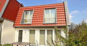 A two-story house with a red-tiled roof, two windows, and a door. - Kapitänshaus Tordalk (Norderney)