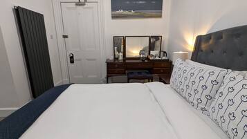 A bedroom with a bed, a dresser, a mirror, and a painting on the wall.