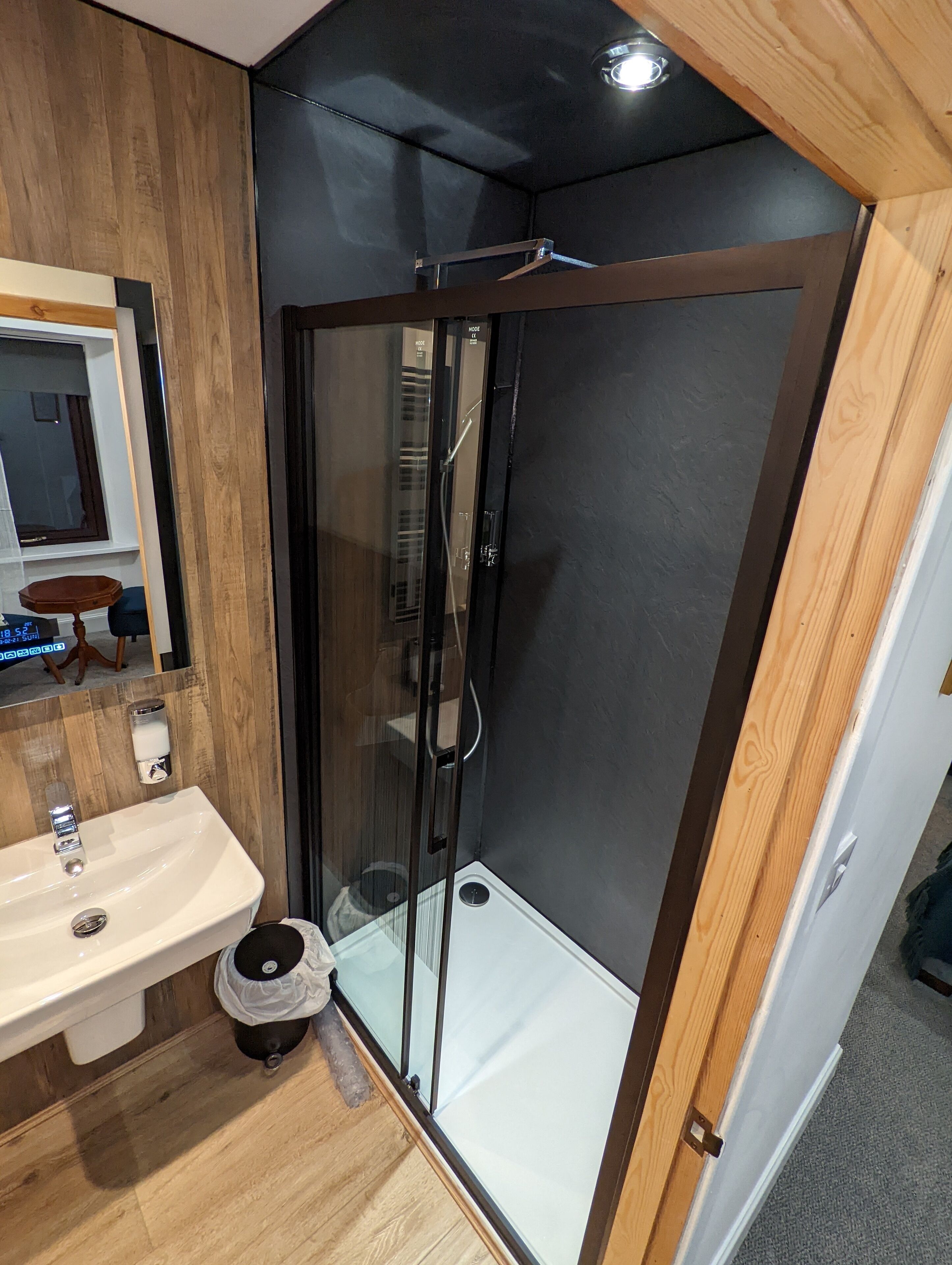 Ein modernes Badezimmer mit Duschkabine aus Glas, einem Holzwaschtisch und einem Spiegel.