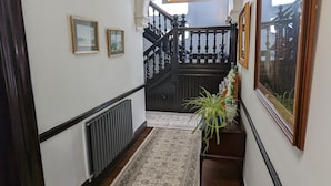 A hallway with a patterned carpet, black railing, and framed pictures on the walls. - Cambeth Lodge Guesthouse (Inverness)