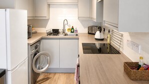 Une cuisine moderne équipée d’un lave-linge, d’un évier, d’un grille-pain et d’une bouilloire.