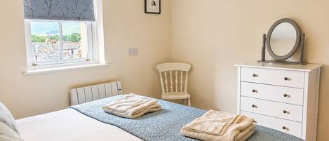 A bedroom with a bed, a dresser, a chair, and a window with a view.