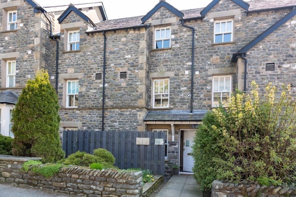 A stone building with multiple windows and a door, surrounded by greenery and a wooden fence. - Howgills Apartment 10 (self-catering accommodation with free parking and Wi-Fi) (Sedbergh)