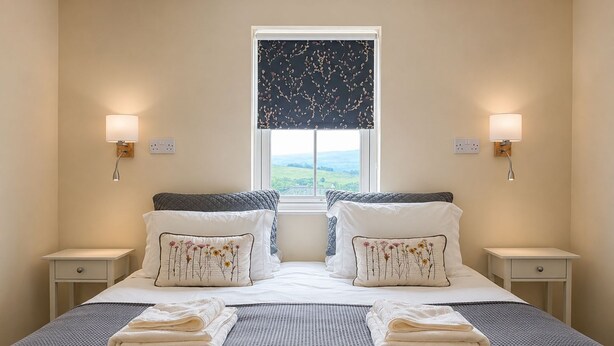 A double bed with two nightstands, a window with a view, and decorative pillows. - Howgills Apartment 11 (self-catering accommodation with free parking and Wi-Fi) (Sedbergh)