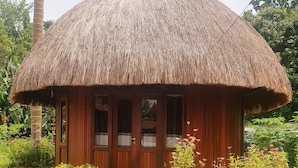A thatched-roof hut with wooden walls and a concrete pathway leading to it. - Korpak Villa & Resort Raja Ampat (Waisai)
