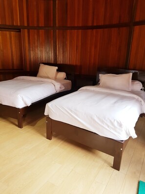 Two wooden beds with white bedding in a room with wooden paneling on the walls. - Korpak Villa & Resort Raja Ampat (Waisai)