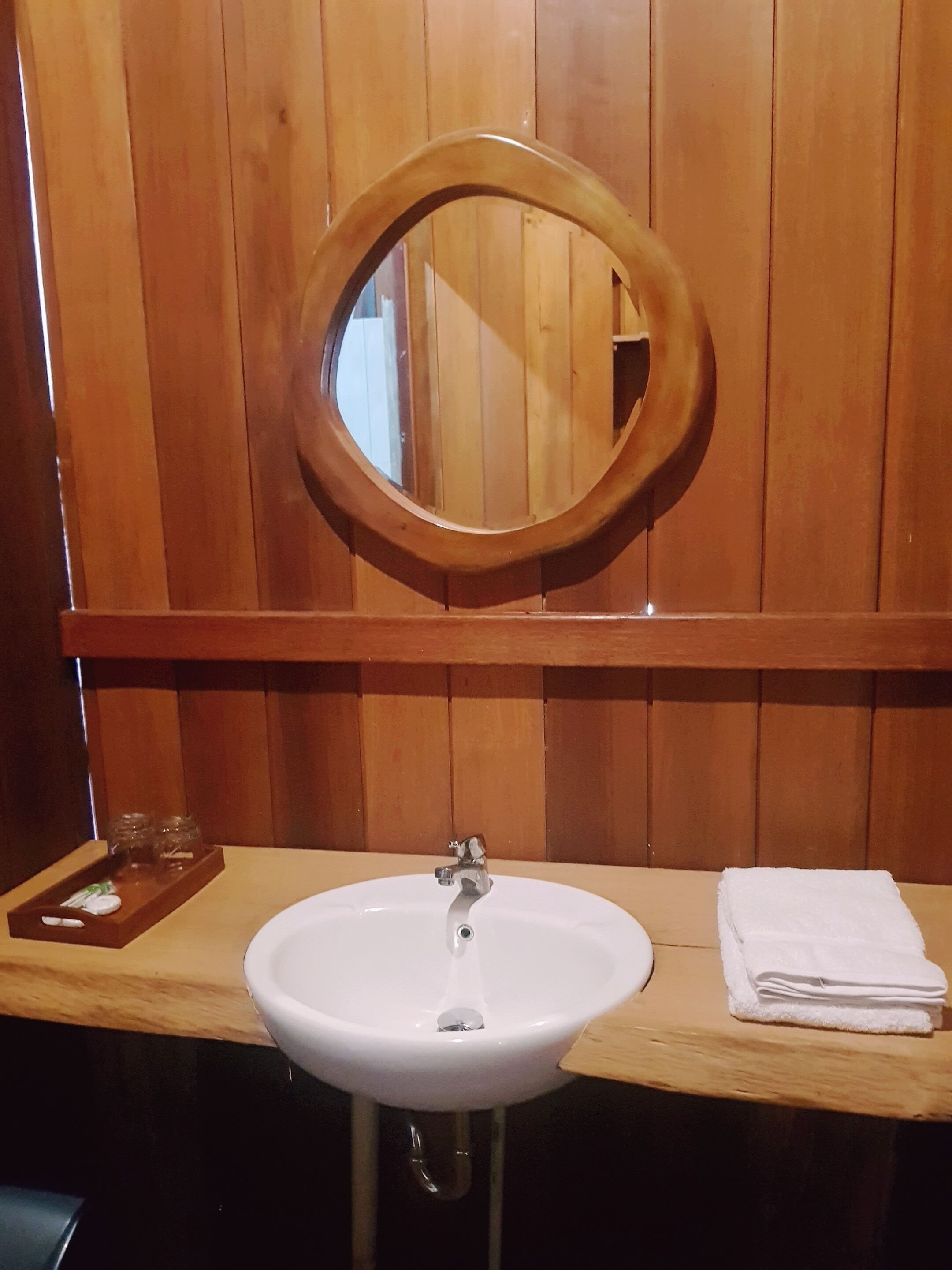 A wooden vanity with a white sink, a mirror, and a towel.