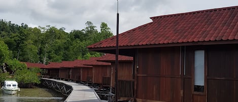 Un muelle de madera que lleva a bungalows sobre el agua, con un barco amarrado al final.