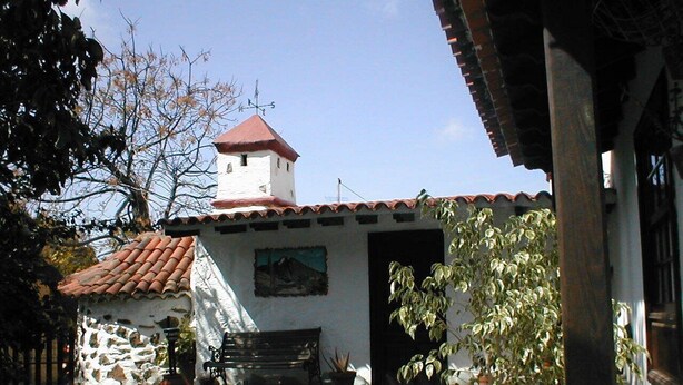 A small building with a red-tiled roof, a stone wall, and a wooden bench. - RURAL HOUSE FINCA PARAISO. for a fantastic stay north of Tenerife (San Cristóbal de La Laguna)