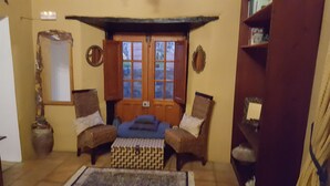 A cozy room with a wooden bench, two chairs, a small rug, and a bookshelf. - RURAL HOUSE FINCA PARAISO. for a fantastic stay north of Tenerife (San Cristóbal de La Laguna)