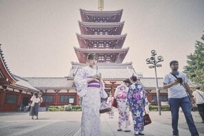 Une pagode japonaise traditionnelle à plusieurs niveaux, un chemin pavé et des personnes vêtues de costumes traditionnels.