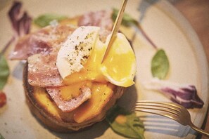 A close-up of a breakfast dish with eggs, ham, and a slice of bread.
