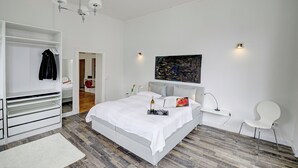 Ein modernes Schlafzimmer mit Bett, Kleiderschrank, Nachttisch, Stuhl und einem Bild an der Wand.