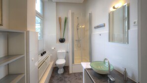 Ein modernes Badezimmer mit einer Duschkabine, einem Waschbecken aus Glas und einer weißen Toilette.