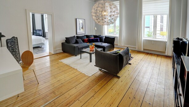 Ein modernes Wohnzimmer mit einem grauen Sofa, einem Couchtisch und Holzboden.