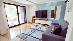 Un salon moderne avec un téléviseur à écran plat, un canapé gris, une table basse et un tapis à rayures.