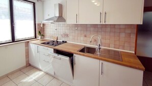 Une cuisine moderne avec des meubles blancs, un plan de travail en bois, un évier en acier inoxydable et un lave-vaisselle.