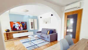 Un salon comprenant un canapé, une table basse, un téléviseur et un coin repas.