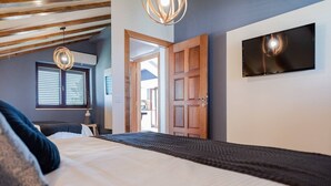 A bedroom with a bed, a TV mounted on the wall, and a wooden door. - Zen Luxury Apartments (Zadar)