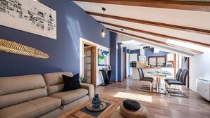 A modern living room with a sofa, coffee table, and dining area. - Zen Luxury Apartments (Zadar)