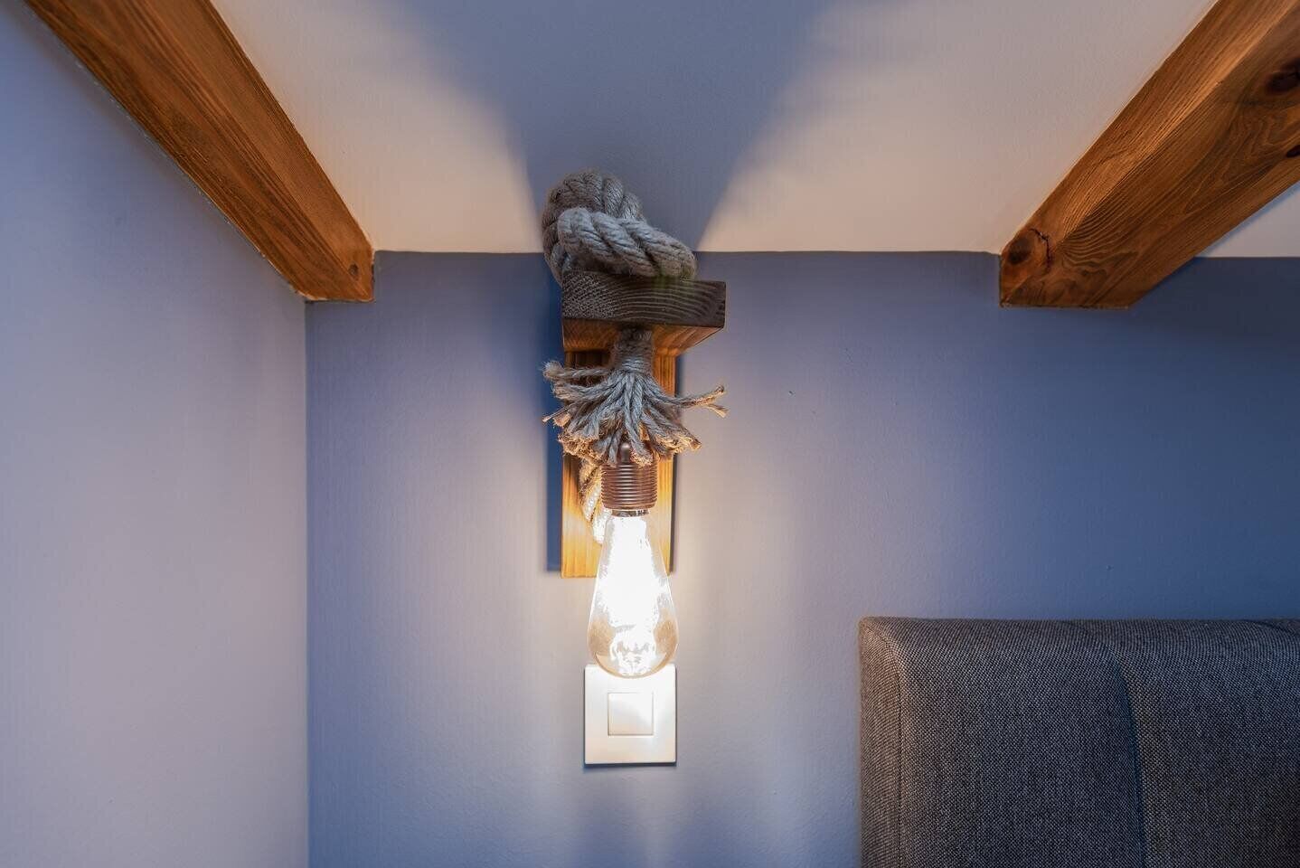 Una lámpara de pared con diseño rústico, pared texturizada y vigas de madera a la vista.