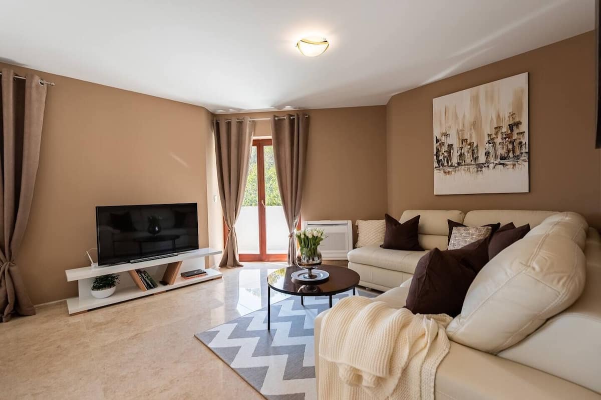A modern living room with a flat-screen TV, sofa, coffee table, and a painting on the wall.