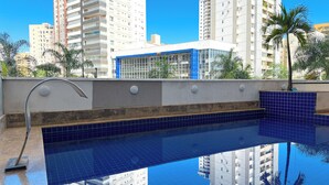 A swimming pool with blue tiles, surrounded by high-rise buildings and palm trees. - STAY Sun Square (Goiania)