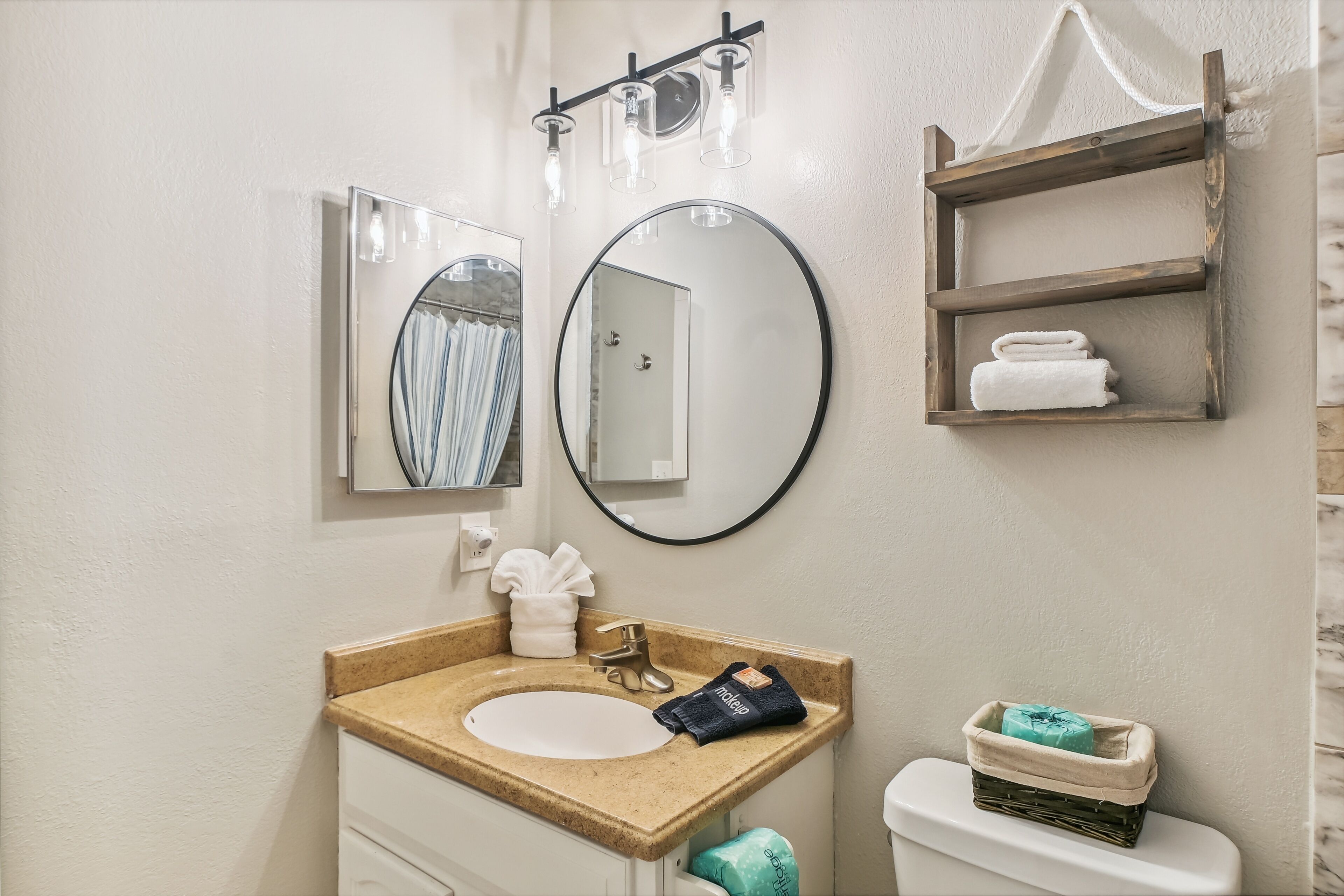 A bathroom with a sink, mirror, towel rack, and a small shelf with toiletries.
