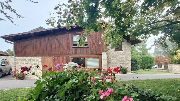 Ein modernes, zweistöckiges Haus mit Stein Fundament und Holzverkleidung, umgeben von einem gepflegten Garten mit blühenden Pflanzen.
