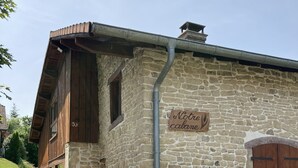 Ein Steinhaus mit Holzfassade, einem Schild mit der Aufschrift "Notre cabane" und Blumentöpfen am Eingang.