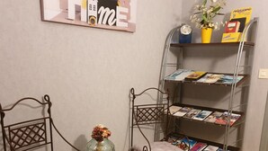 A cozy room with a metal chair, a small wooden table, a metal shelf with books, and a 'Home' sign on the wall. - Au Fil des Lacs (Précy-Saint-Martin)