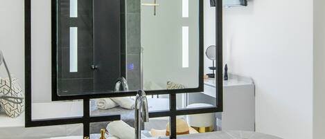 A modern bathroom with a large mirror, a white sink, and a wooden countertop.