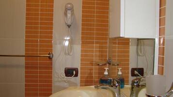 A bathroom with a white sink, two mirrors, a hairdryer, and a towel rack.