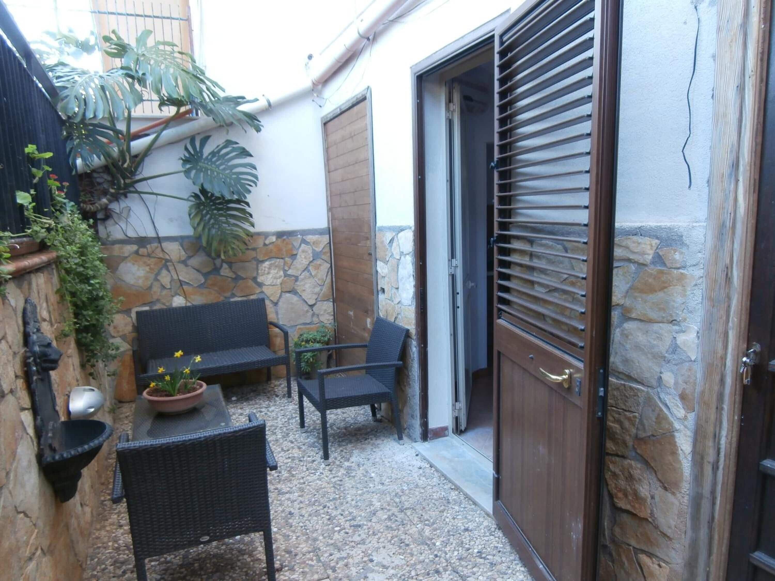 A patio area with wicker furniture, a stone wall, and a wooden door.