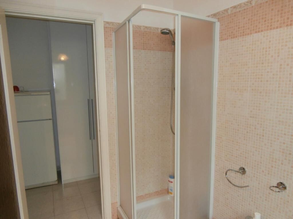 A bathroom with a shower enclosure, a toilet, and a sink.