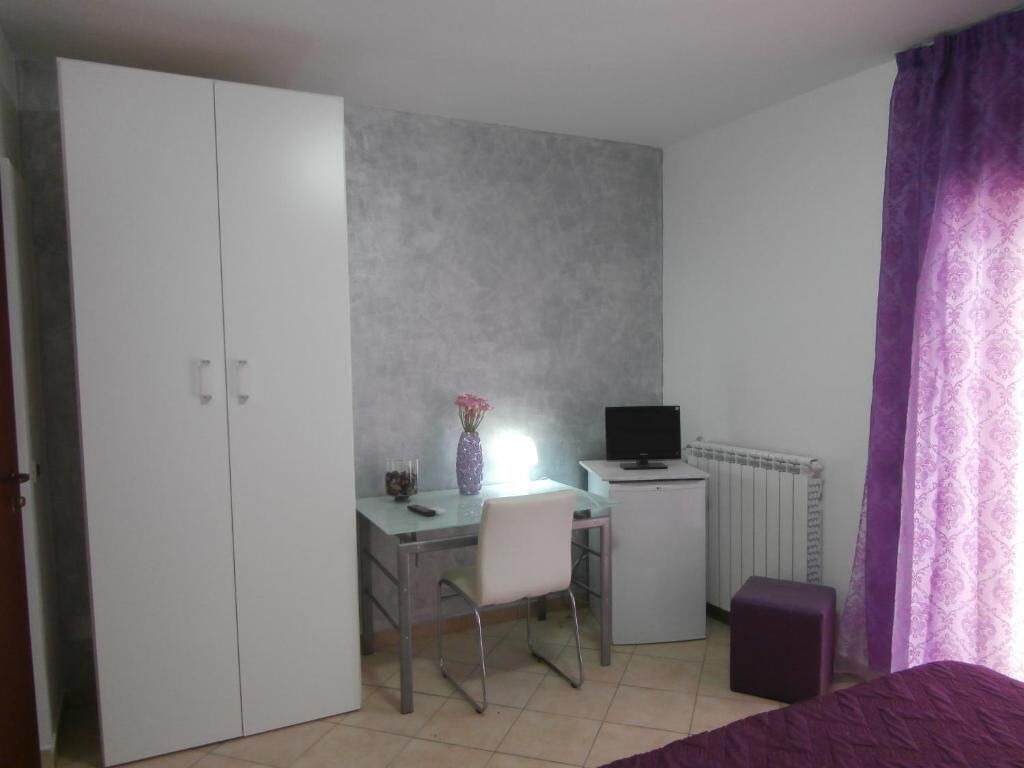 Un dormitorio con cama, escritorio con silla, televisor y armario.
